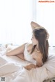 A woman laying on a bed in a white lingerie.