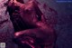 A naked woman laying on the ground covered in blood.