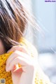 A close up of a woman's hand holding a yellow scarf.