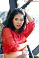 A woman in a red blouse sitting on a bench.