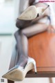 A woman sitting on top of a wooden table wearing high heels.