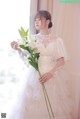 A woman in a wedding dress holding a bouquet of flowers.