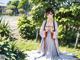 A woman in a white dress sitting in the grass.