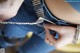 A woman is sewing a pair of jeans with a pair scissors.