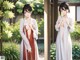 A woman in a white kimono standing in front of a window.