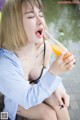 A woman sitting on a bench drinking from a bottle.