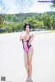 A woman in a pink and black bathing suit standing on a beach.