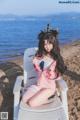 A woman sitting on top of a white chair on a beach.