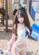 A woman in a white bikini sitting on a playground.