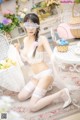 A woman in a white lingerie sitting on the floor.