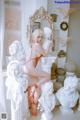 A woman in an orange bathing suit sitting on a white pedestal.