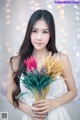 A woman in a white dress holding a bunch of flowers.