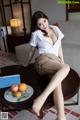 A woman sitting on top of a table next to a plate of fruit.