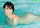 A naked woman in a swimming pool smiling at the camera.