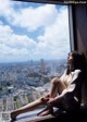 A woman sitting on a window sill looking out a window.