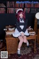 A woman sitting on top of a desk in front of a book shelf.