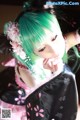 A woman with green hair wearing a black and pink kimono.