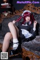 A woman in a maid outfit sitting on a couch.