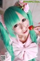 A woman with green hair holding a strawberry in her hand.