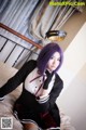 A woman in a school uniform sitting on a bed.