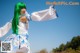 A woman with green hair and a white shirt is dancing.