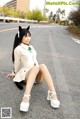 A woman sitting on the side of a road with a cat tail.