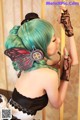 A woman with green hair wearing a black top hat and gloves.