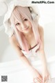 A woman with pink hair wearing headphones and a bunny hat.