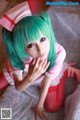 A woman with green hair wearing a pink nurse outfit.