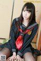 A woman in a school uniform sitting on the floor.