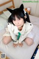 A woman in a cat costume sitting on a bed.