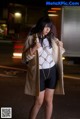 A woman standing in the middle of a street at night.
