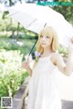 A woman in a white dress holding an umbrella.