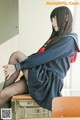A woman in a school uniform sitting on a chair.