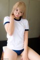 A woman in a white shirt and blue panties sitting on a table.