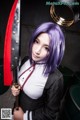A woman with purple hair holding a large knife.