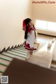 A woman in a school uniform standing on a set of stairs.