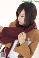 A woman in a brown jacket and a maroon scarf.