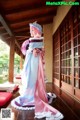 A woman in a pink and blue dress holding a fan.