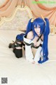 A woman with long blue hair sitting on a bed.
