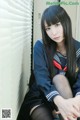A woman in a school uniform sitting on a window sill.