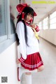 A woman in a school uniform leaning against a wall.