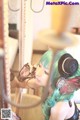 A woman with green hair wearing a top hat and headphones.
