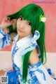 A woman with long green hair wearing a blue and white dress.