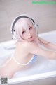 A woman in a bathtub with headphones on.