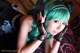 A woman with green hair laying on a bed.
