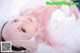 A woman with pink hair laying on a bed.