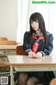 A woman in a school uniform sitting at a desk.