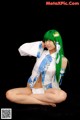 A woman with green hair sitting on the ground.