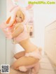 A woman in a bunny costume holding a carrot.